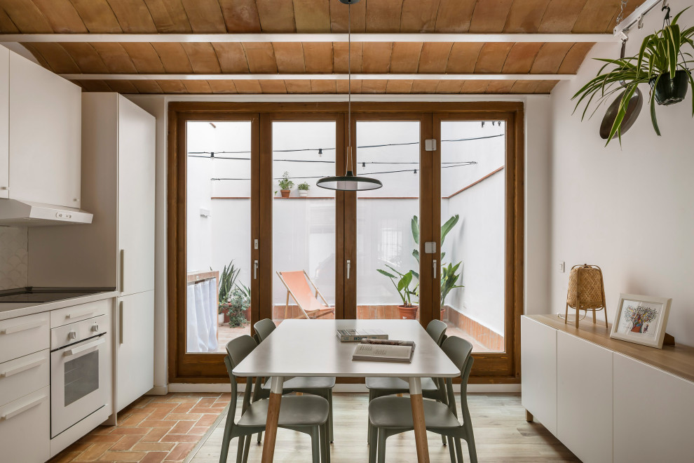 Esempio di una piccola sala da pranzo aperta verso il soggiorno mediterranea con pareti bianche, pavimento in laminato, pavimento marrone e travi a vista