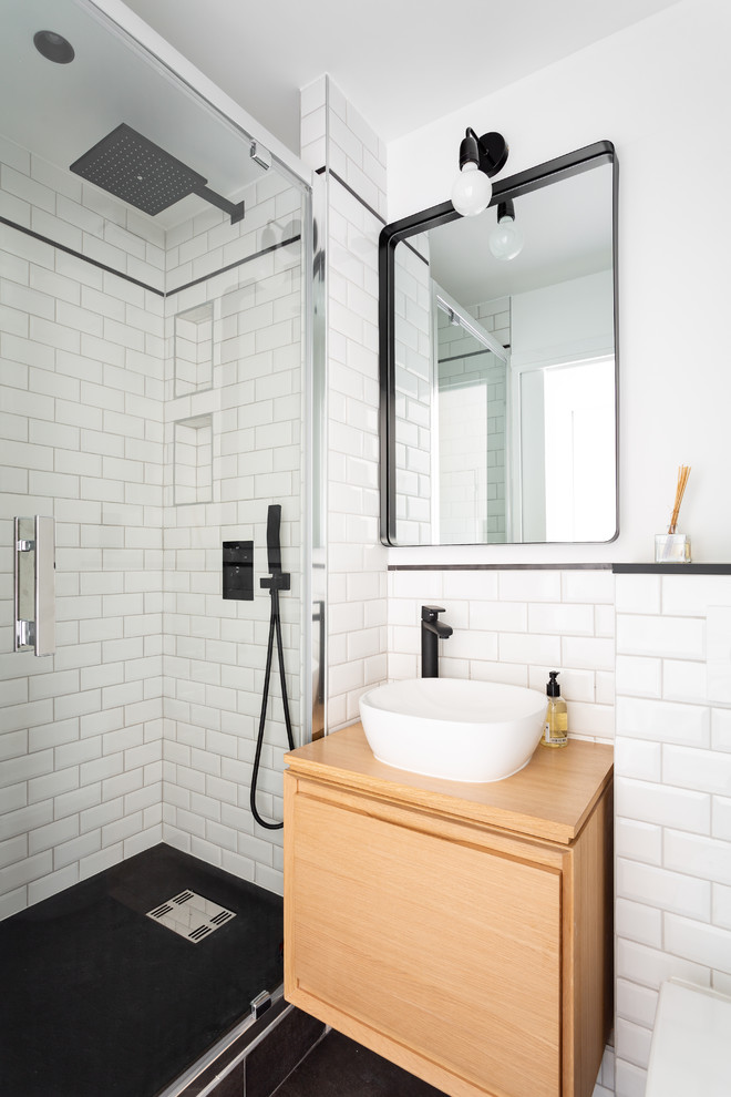 Inspiration for a small contemporary master bathroom in London with flat-panel cabinets, light wood cabinets, a corner shower, white tile, subway tile, white walls, a vessel sink, wood benchtops, black floor, ceramic floors, a hinged shower door and beige benchtops.