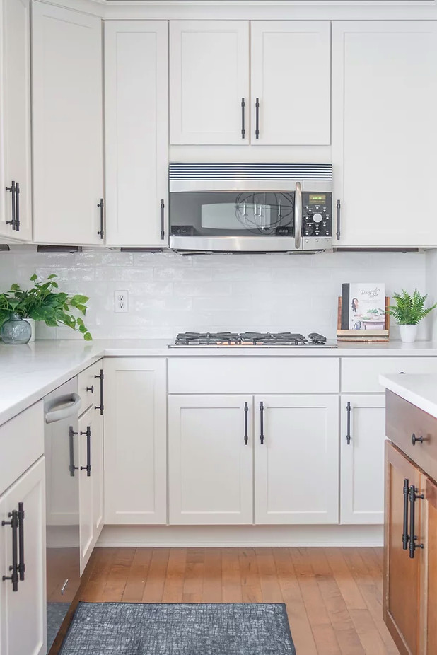 Large transitional u-shaped medium tone wood floor and brown floor eat-in kitchen photo in Minneapolis with a single-bowl sink, shaker cabinets, white cabinets, quartz countertops, white backsplash, porcelain backsplash, stainless steel appliances, an island and white countertops