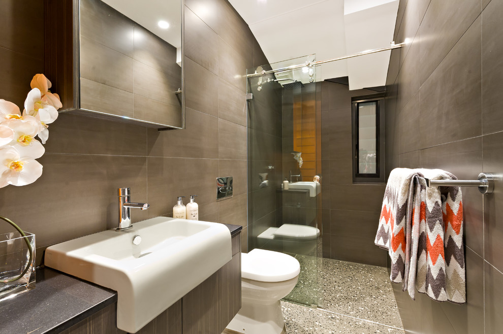 Contemporary 3/4 bathroom in Sydney with flat-panel cabinets, dark wood cabinets, a curbless shower, a one-piece toilet, brown walls, an integrated sink, brown tile and a sliding shower screen.