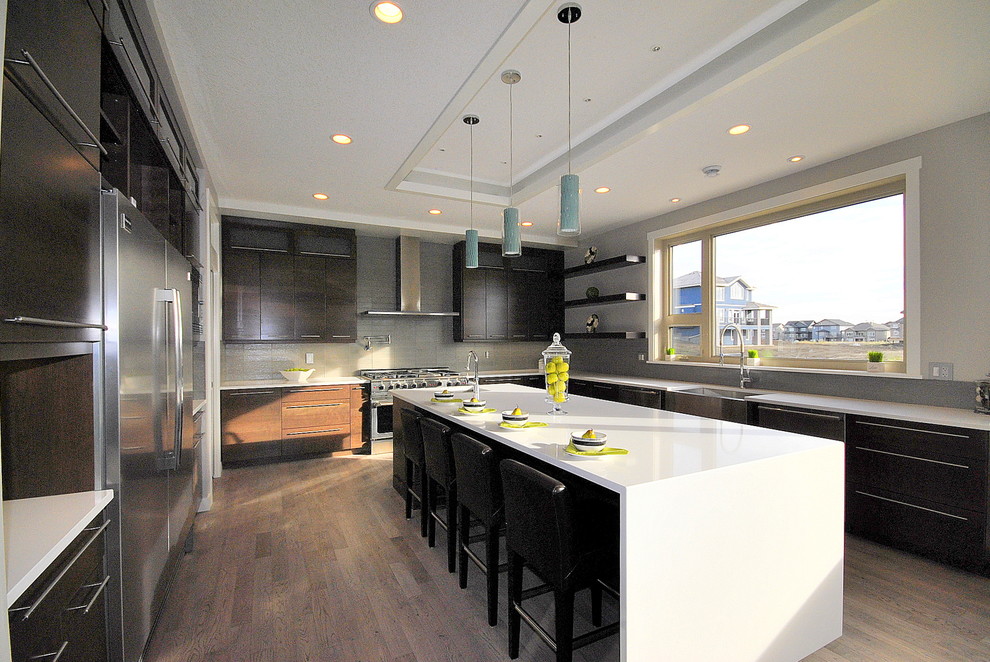 This is an example of a contemporary u-shaped eat-in kitchen in Edmonton with a single-bowl sink, flat-panel cabinets, medium wood cabinets, quartz benchtops, black splashback, glass tile splashback and stainless steel appliances.