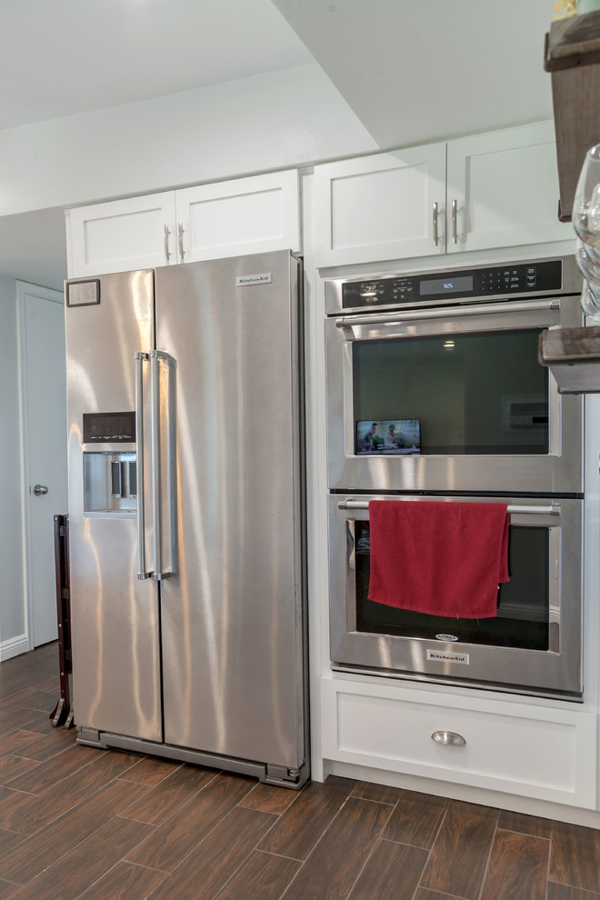 Mid-sized transitional u-shaped laminate floor and brown floor open concept kitchen photo in Phoenix with an undermount sink, recessed-panel cabinets, white cabinets, granite countertops, multicolored backsplash, mosaic tile backsplash and stainless steel appliances