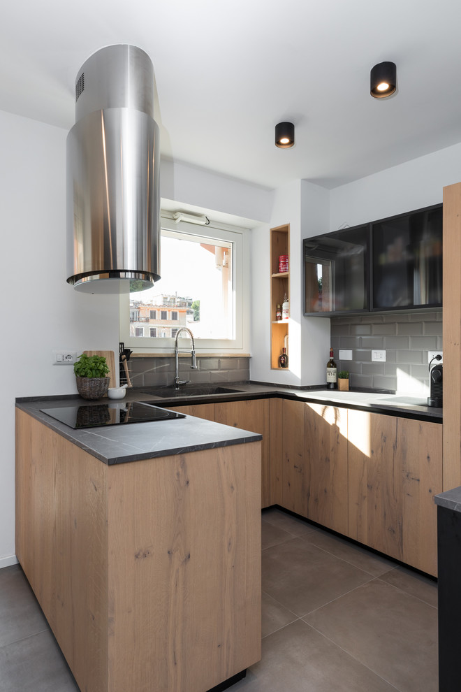 Inspiration for a contemporary u-shaped kitchen in Rome with an integrated sink, flat-panel cabinets, medium wood cabinets, grey splashback, subway tile splashback, a peninsula, grey floor and black benchtop.