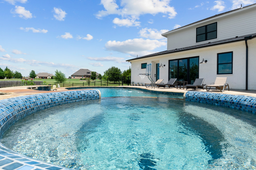This is an example of a large country backyard kidney-shaped natural pool in Dallas with a hot tub and concrete slab.