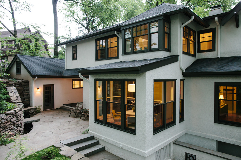 This is an example of a large transitional two-storey stucco white house exterior in New York with a hip roof and a shingle roof.