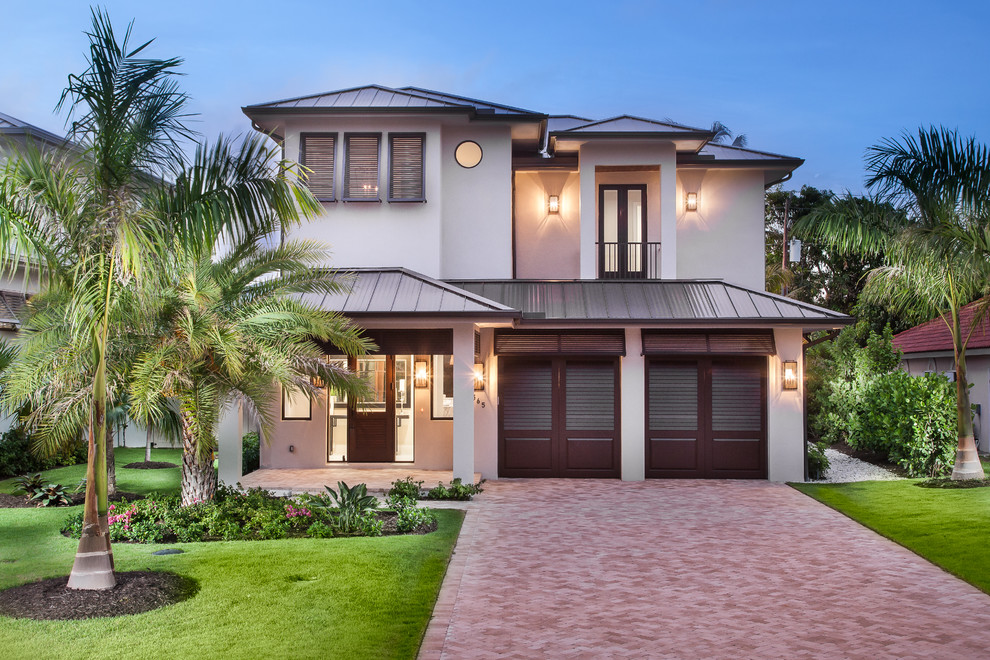 This is an example of a large beach style two-storey stucco beige exterior in Miami with a hip roof.
