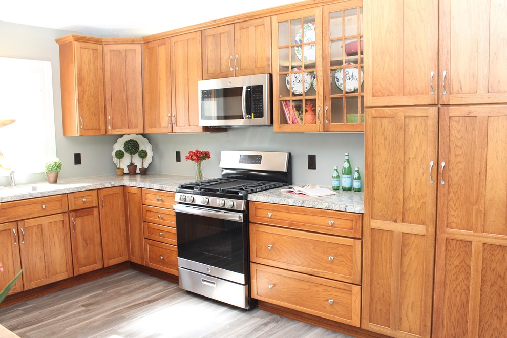 Large transitional l-shaped medium tone wood floor and gray floor enclosed kitchen photo in New York with glass-front cabinets, medium tone wood cabinets and stainless steel appliances