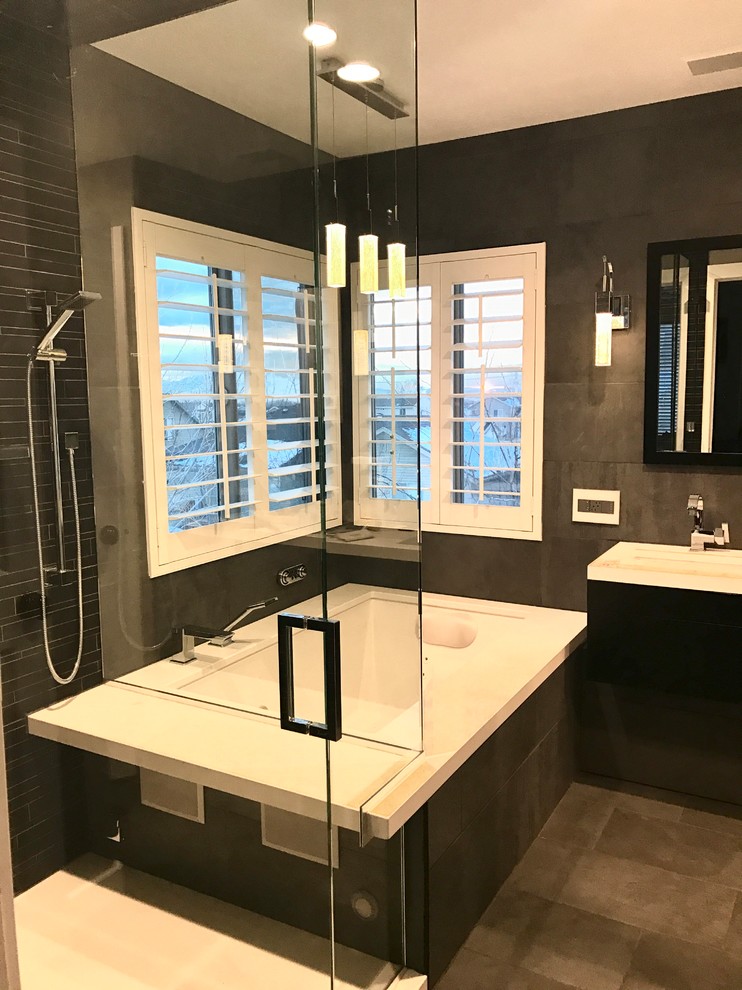 Mid-sized contemporary master bathroom in Salt Lake City with furniture-like cabinets, black cabinets, an undermount tub, a corner shower, a wall-mount toilet, black tile, porcelain tile, grey walls, porcelain floors, an undermount sink, grey floor, a hinged shower door and engineered quartz benchtops.