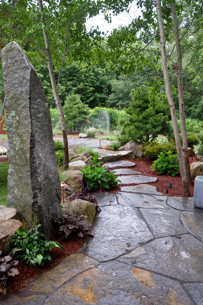 Design ideas for a large country backyard patio in Boston with natural stone pavers.