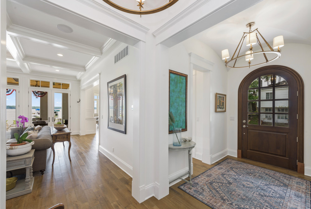 This is an example of a traditional foyer in Indianapolis with white walls, medium hardwood floors, a single front door, a dark wood front door, brown floor and vaulted.