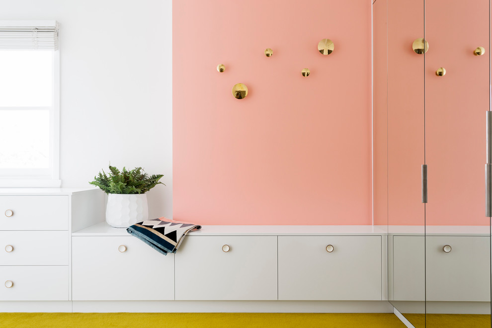 Design ideas for a mid-sized contemporary gender-neutral walk-in wardrobe in Melbourne with flat-panel cabinets, white cabinets, carpet and yellow floor.
