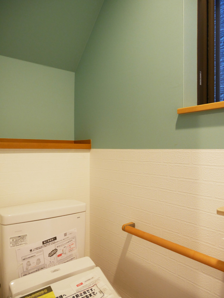 Imagen de aseo actual pequeño con sanitario de dos piezas, paredes verdes, suelo de contrachapado, suelo marrón, papel pintado y papel pintado