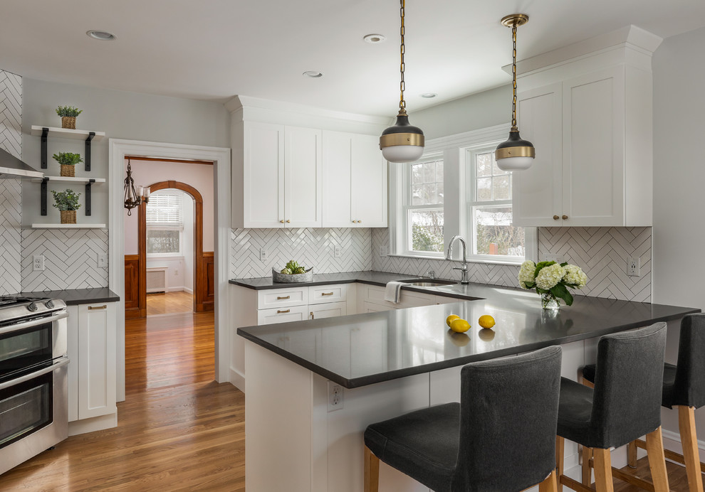 Enclosed kitchen - mid-sized transitional u-shaped light wood floor and brown floor enclosed kitchen idea in Boston with an undermount sink, shaker cabinets, white cabinets, quartz countertops, gray backsplash, ceramic backsplash, stainless steel appliances, a peninsula and gray countertops