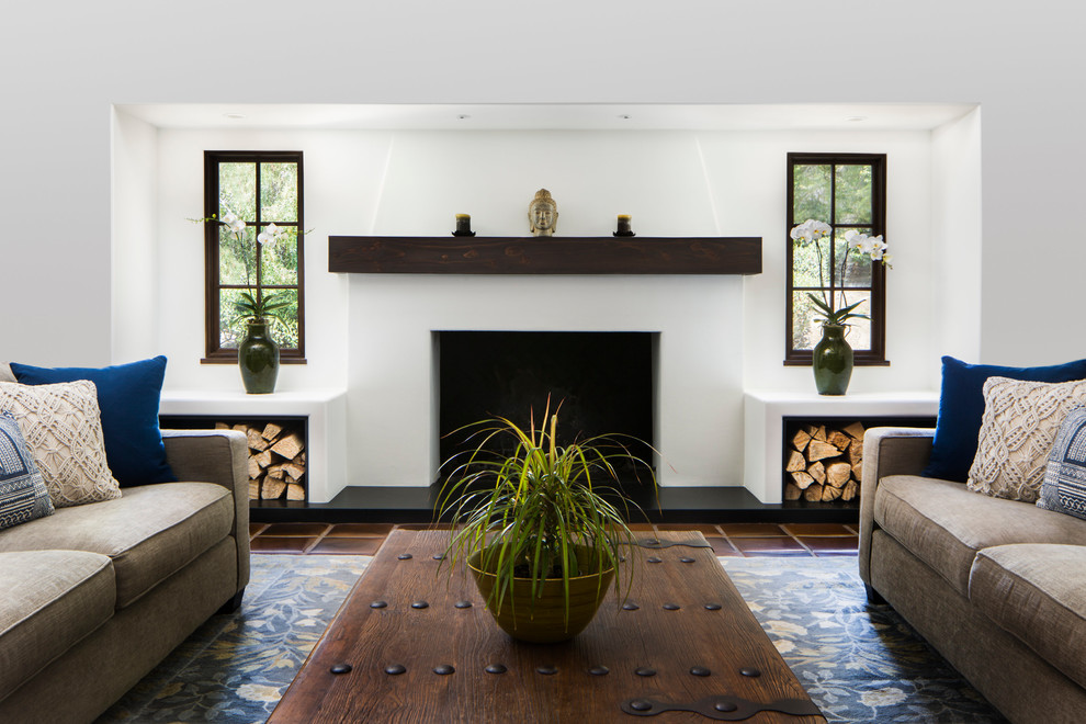 Inspiration for a mid-sized mediterranean enclosed living room in Santa Barbara with white walls, terra-cotta floors, a standard fireplace, a plaster fireplace surround and brown floor.