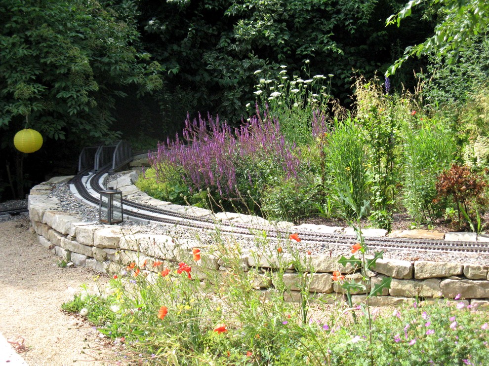 Großer Klassischer Garten neben dem Haus mit Natursteinplatten, Spielgerät und direkter Sonneneinstrahlung in Hannover