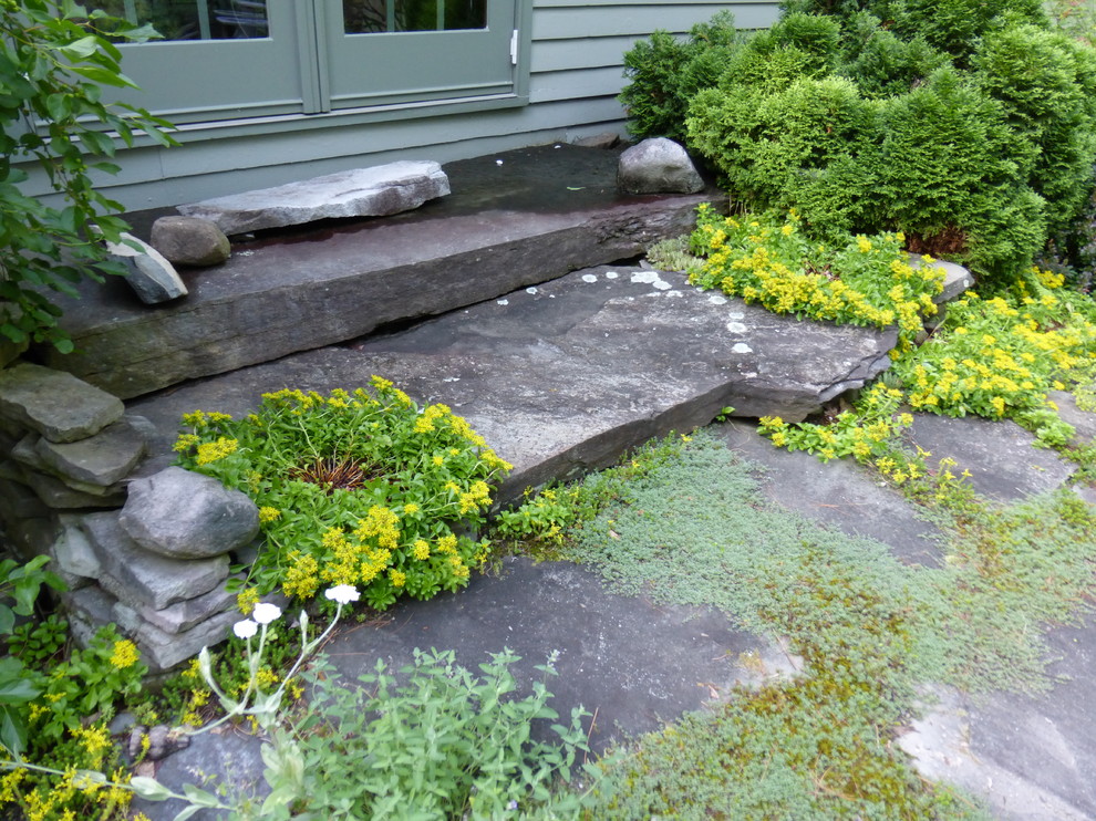 Large country side yard full sun xeriscape in New York with natural stone pavers for summer.