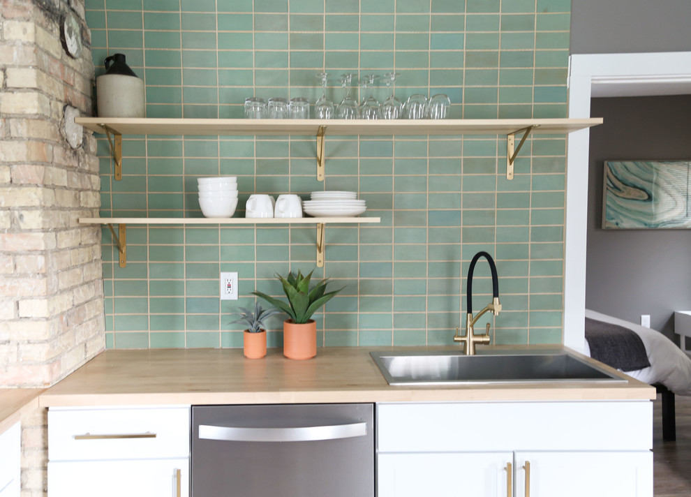 Inspiration for a small transitional l-shaped light wood floor and brown floor open concept kitchen remodel in Minneapolis with a drop-in sink, flat-panel cabinets, white cabinets, wood countertops, green backsplash, ceramic backsplash, stainless steel appliances, no island and brown countertops