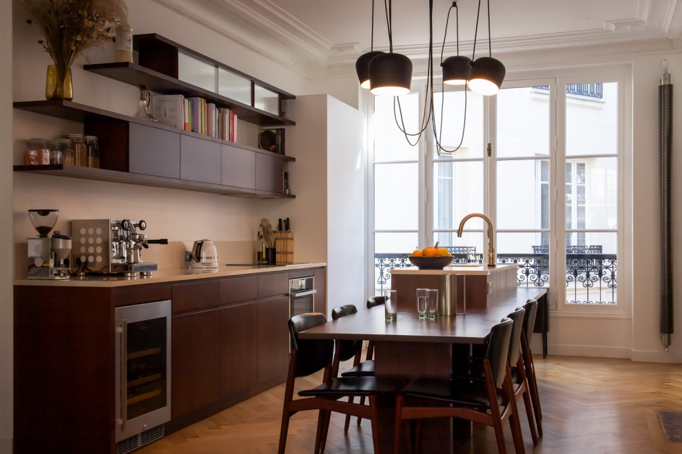Large contemporary galley kitchen/diner in Paris with a submerged sink, beaded cabinets, dark wood cabinets, marble worktops, beige splashback, marble splashback, black appliances, dark hardwood flooring, an island, brown floors and beige worktops.