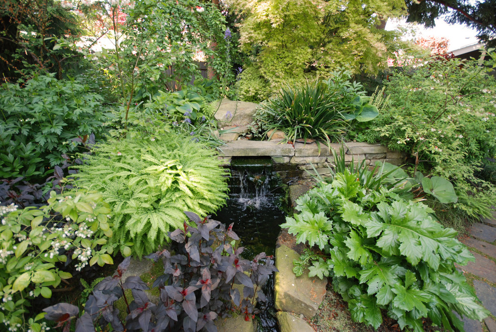 Traditional backyard shaded garden in Seattle with a water feature.