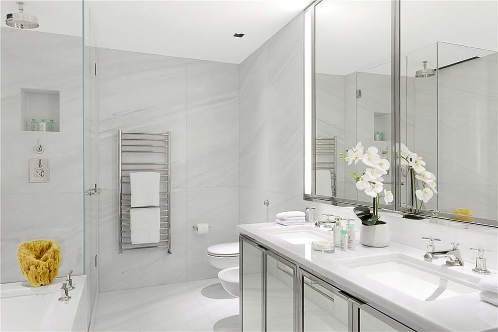 Mid-sized contemporary master bathroom in London with glass-front cabinets, white cabinets, a drop-in tub, an open shower, a wall-mount toilet, white tile, marble, white walls, marble floors, a drop-in sink, marble benchtops, white floor and a sliding shower screen.