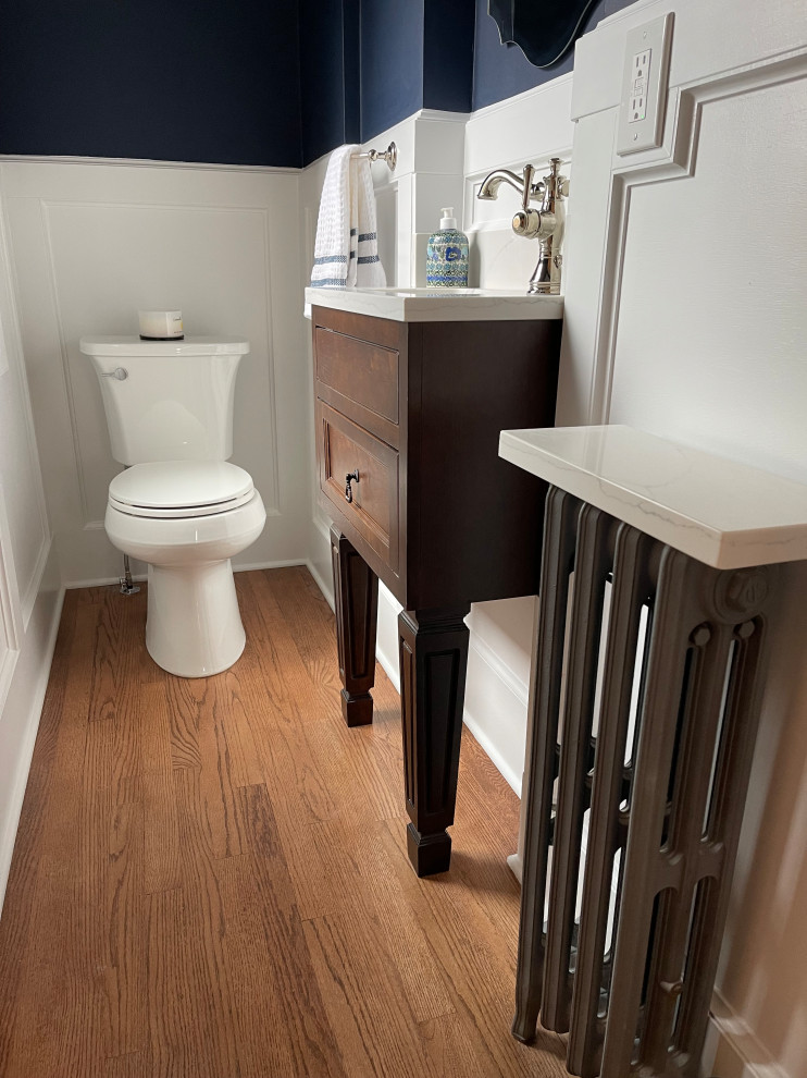 Exemple d'un petit WC et toilettes chic en bois foncé avec un placard à porte shaker, WC séparés, un mur bleu, un sol en bois brun, un lavabo encastré, un plan de toilette en quartz modifié, un sol marron, un plan de toilette blanc, meuble-lavabo sur pied et boiseries.