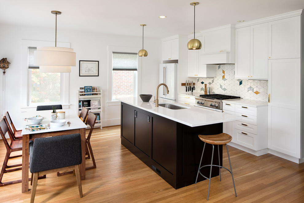 Photo of a transitional galley eat-in kitchen in Seattle with an undermount sink, recessed-panel cabinets, white cabinets, multi-coloured splashback, porcelain splashback, white appliances, medium hardwood floors, with island, grey floor and white benchtop.