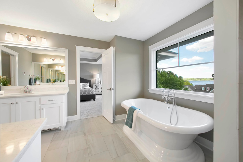 Large transitional master bathroom in Minneapolis with white cabinets, a freestanding tub, white tile, grey walls, ceramic floors, granite benchtops and shaker cabinets.