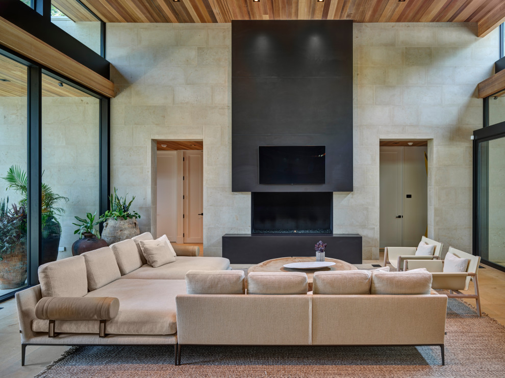 Esempio di un grande soggiorno design aperto con pavimento in pietra calcarea, pareti beige, camino classico, TV a parete, pavimento beige e soffitto in legno