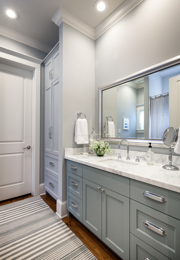Photo of a mid-sized transitional bathroom in Houston with shaker cabinets, an undermount sink, marble benchtops, grey cabinets, a shower/bathtub combo, grey walls, medium hardwood floors, an alcove tub, a one-piece toilet and subway tile.