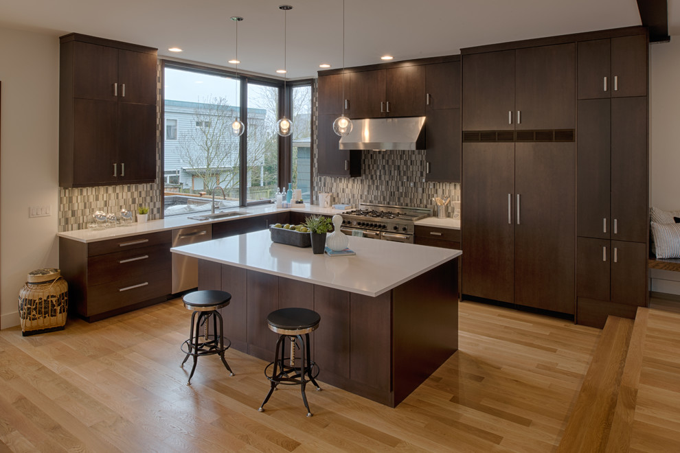 Large contemporary l-shaped open plan kitchen in Seattle with a single-bowl sink, flat-panel cabinets, dark wood cabinets, quartz benchtops, brown splashback, ceramic splashback, stainless steel appliances, dark hardwood floors and with island.