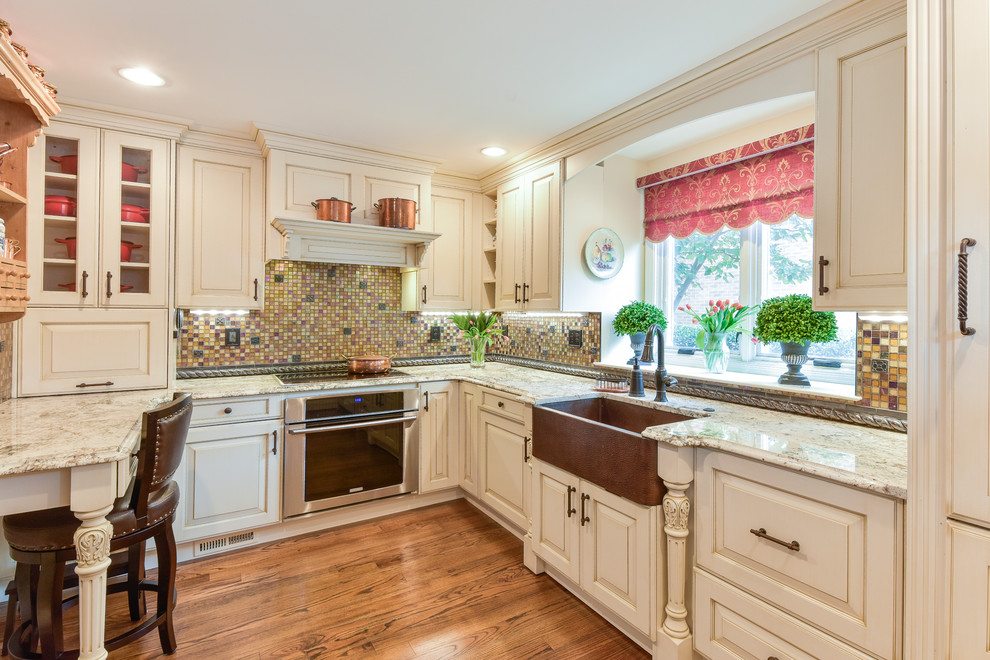 Photo of a mid-sized transitional u-shaped kitchen in DC Metro with an undermount sink, raised-panel cabinets, white cabinets, granite benchtops, multi-coloured splashback, mosaic tile splashback, panelled appliances, medium hardwood floors, a peninsula and brown floor.