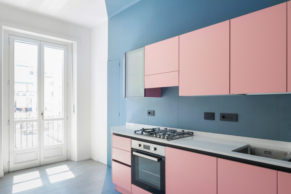 Modern inredning av ett vit linjärt vitt kök, med en undermonterad diskho, bänkskiva i kvarts, blått stänkskydd, stänkskydd i keramik, rostfria vitvaror, klinkergolv i keramik och blått golv