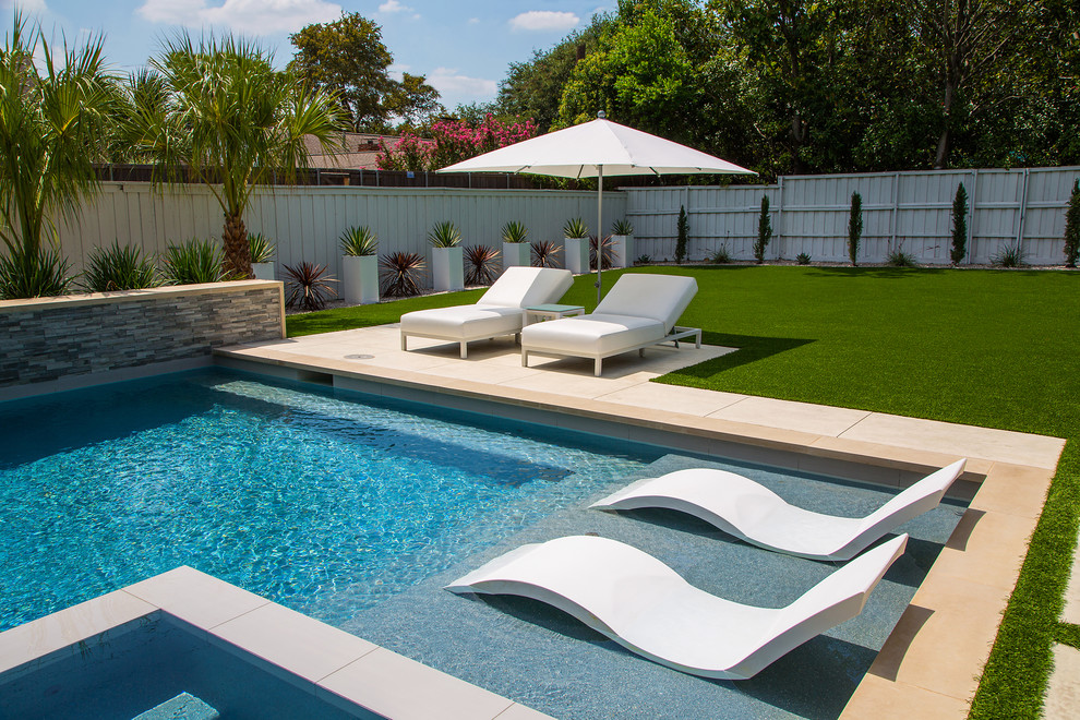 This is an example of a mid-sized modern backyard rectangular pool in Dallas with a hot tub.