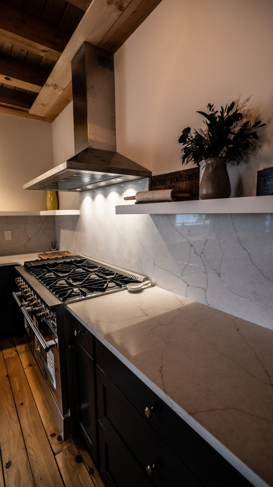 Modern inredning av ett mellanstort vit vitt kök, med en undermonterad diskho, släta luckor, svarta skåp, bänkskiva i kvartsit, vitt stänkskydd, stänkskydd i sten, rostfria vitvaror, mellanmörkt trägolv, en köksö och brunt golv
