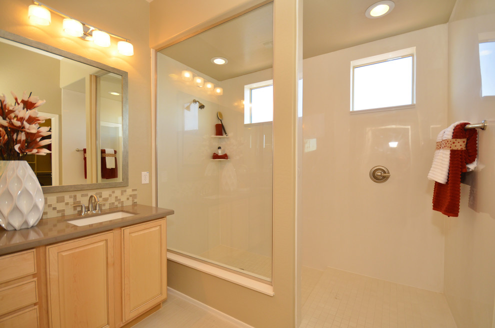 Design ideas for a large contemporary master bathroom in Phoenix with a drop-in sink, recessed-panel cabinets, light wood cabinets, engineered quartz benchtops, a curbless shower, a one-piece toilet, gray tile, porcelain tile, beige walls and porcelain floors.