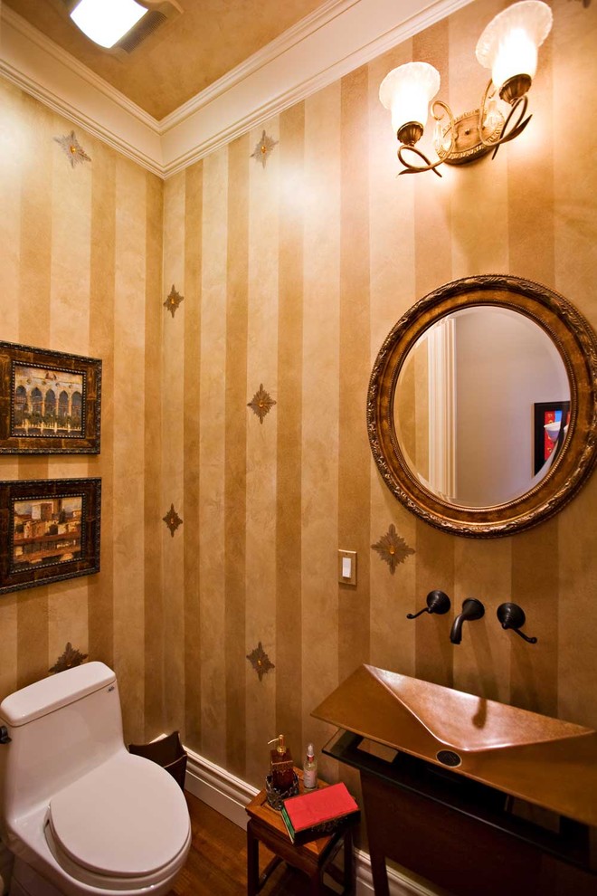 Photo of a small eclectic powder room in San Francisco with furniture-like cabinets, dark wood cabinets, a one-piece toilet, dark hardwood floors, copper benchtops, a vessel sink, yellow tile, yellow walls and brown floor.