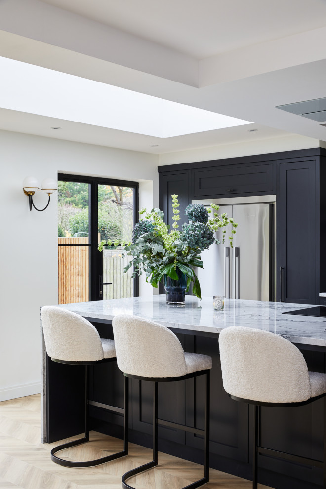Photo of a large traditional l-shaped kitchen/diner in London with recessed-panel cabinets, black cabinets and an island.