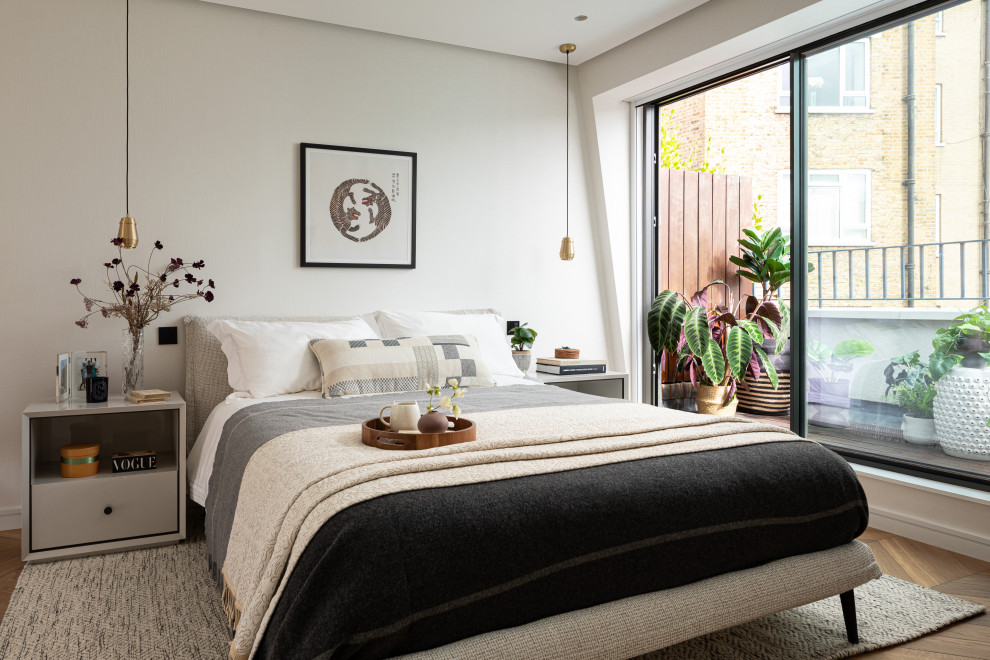 Inspiration for a medium sized contemporary master and cream and black loft bedroom in London with medium hardwood flooring, brown floors and white walls.