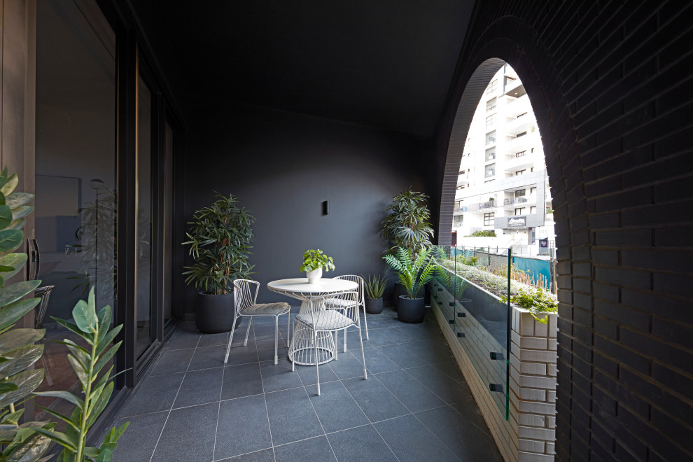 Design ideas for a contemporary balcony in Brisbane with a roof extension and glass railing.