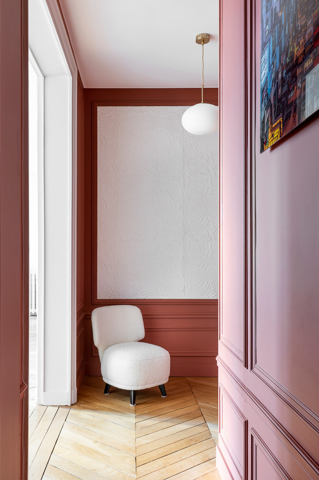 This is an example of a mid-sized transitional hallway in Paris with pink walls and light hardwood floors.