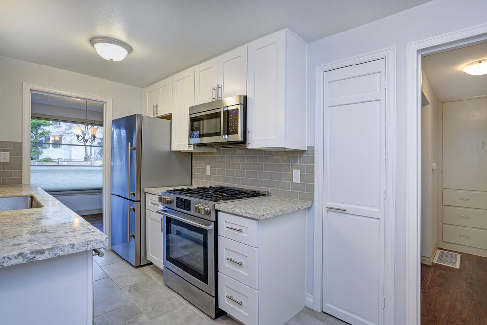 Example of a transitional cement tile floor and beige floor kitchen design with an undermount sink, shaker cabinets, white cabinets, granite countertops, beige backsplash, cement tile backsplash, stainless steel appliances, no island and multicolored countertops