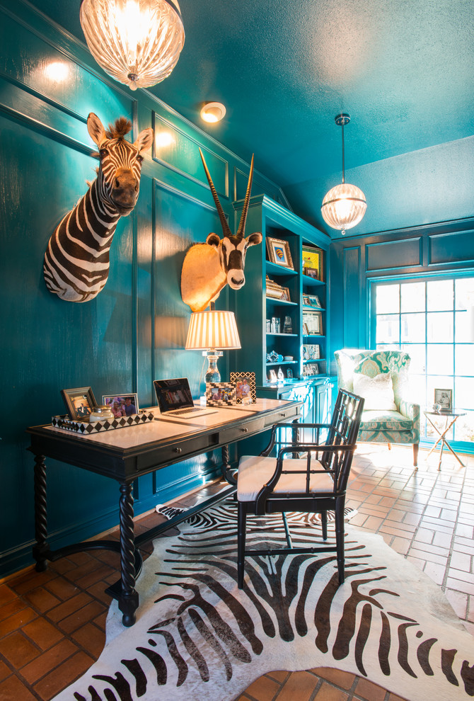 Photo of an eclectic home office in Dallas with blue walls, terra-cotta floors and a freestanding desk.