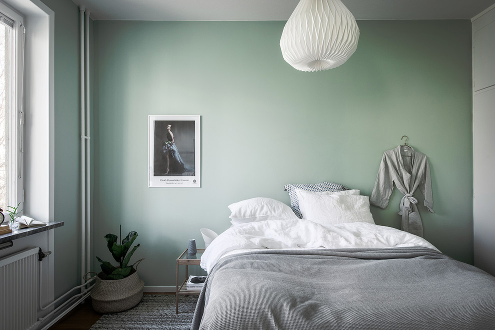 This is an example of a scandinavian master bedroom in Stockholm with green walls.