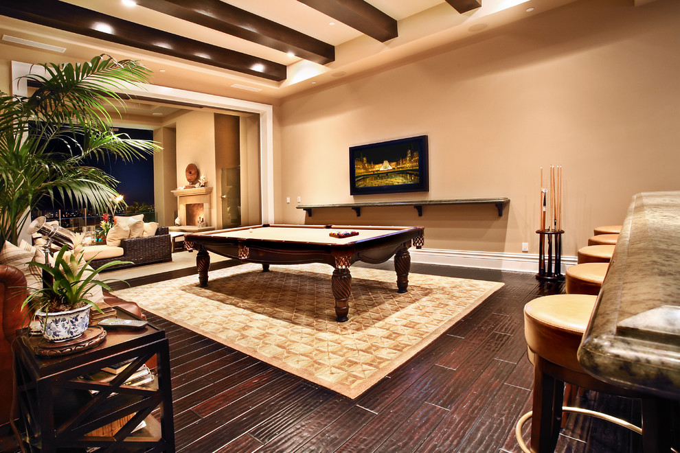 Design ideas for a large tropical enclosed family room in Orange County with beige walls, dark hardwood floors, a built-in media wall, a game room, no fireplace and brown floor.