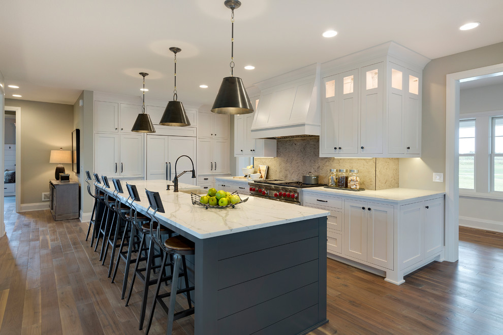 Design ideas for a large transitional l-shaped kitchen in Minneapolis with a farmhouse sink, white cabinets, quartz benchtops, grey splashback, ceramic splashback, with island, shaker cabinets and dark hardwood floors.