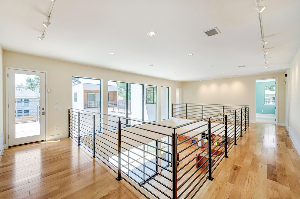 This is an example of a modern hallway in Dallas with white walls and medium hardwood floors.
