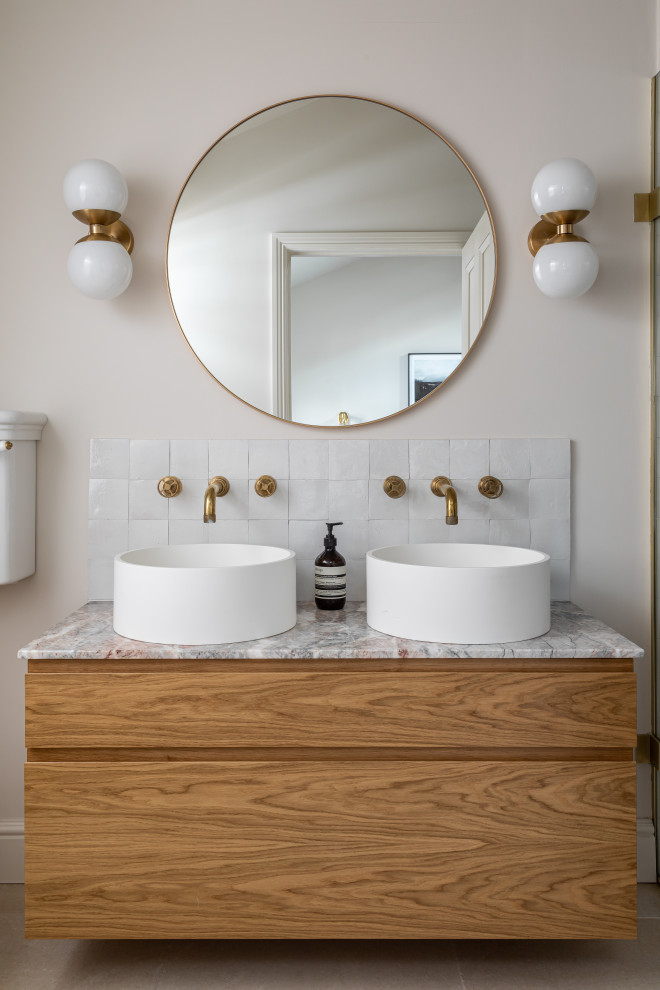 Foto på ett vintage flerfärgad en-suite badrum, med släta luckor, skåp i mellenmörkt trä, vit kakel, vita väggar, ett fristående handfat, marmorbänkskiva och beiget golv