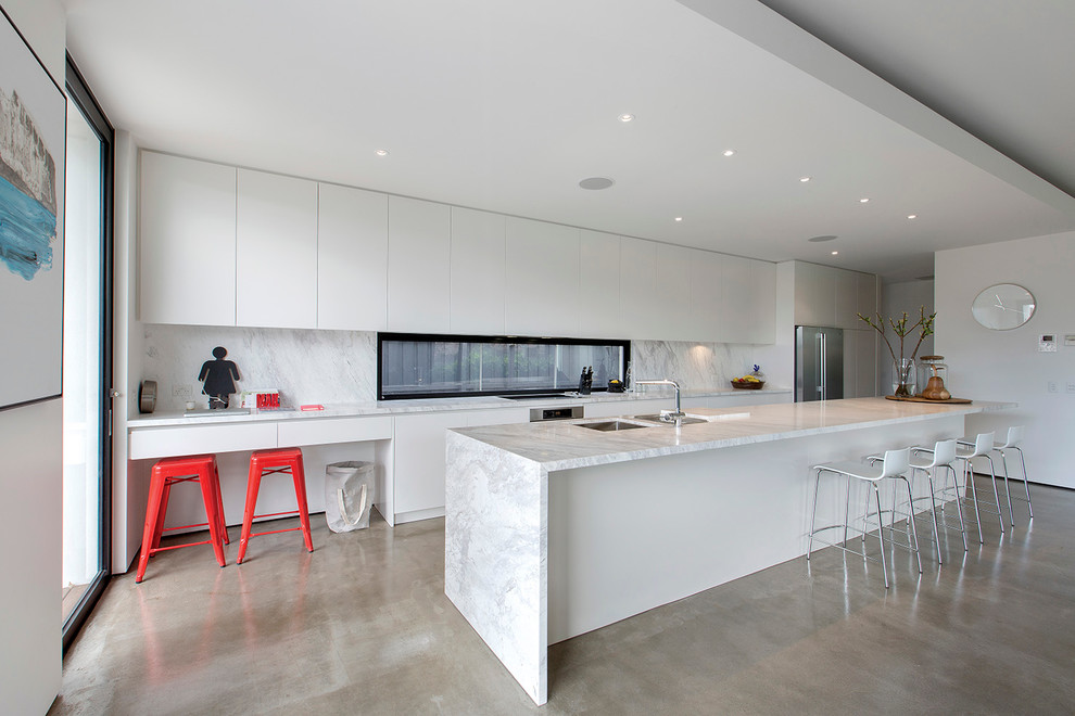 This is an example of a mid-sized contemporary galley eat-in kitchen in Melbourne with white cabinets, concrete floors and with island.