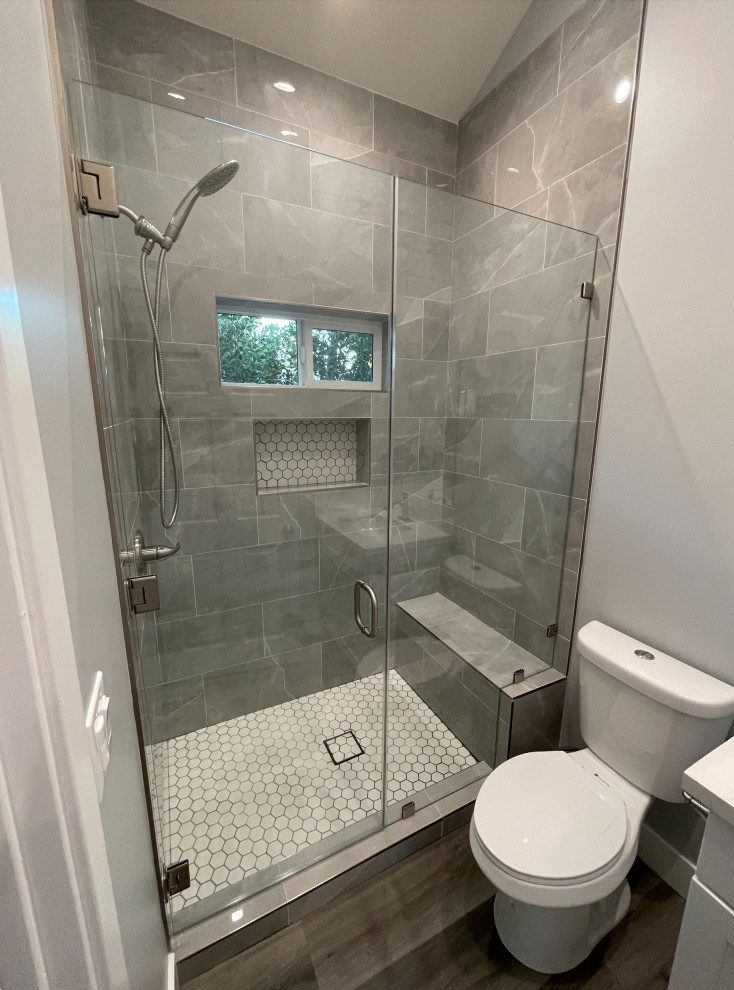 Пример оригинального дизайна: ванная комната среднего размера в стиле модернизм с фасадами в стиле шейкер, белыми фасадами, душем в нише, раздельным унитазом, серой плиткой, керамической плиткой, серыми стенами, полом из винила, душевой кабиной, врезной раковиной, столешницей из кварцита, коричневым полом, душем с распашными дверями, бежевой столешницей, сиденьем для душа, тумбой под одну раковину, напольной тумбой и сводчатым потолком