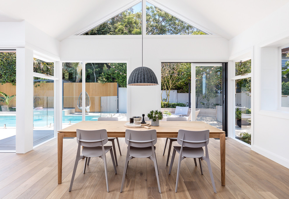 Photo of a beach style open plan dining in Sydney with white walls, medium hardwood floors, brown floor and vaulted.